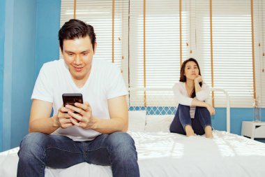 Erkek arkadaşı yatağın ucunda oturup akıllı telefonuyla oyun oynamayı takıntı haline getirmiş. Kız arkadaşını görmezden gelip, beklemekten bıkmış..