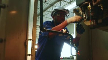 Afrikalı Amerikalı erkek teknisyen soğutucu boruları, otonom çelik kesicileri ve matkapları denetliyor ve verimli bir operasyon için güvenliği sağlıyor..