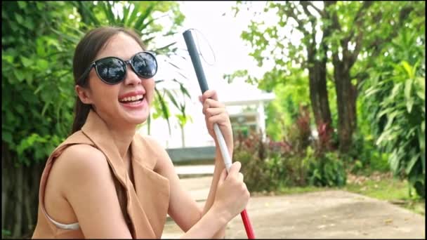 在医院里 戴着墨镜 手持手杖 坐在公园里与医生交谈的美丽的失明的亚洲年轻女子 欢呼着 得到了好消息 接受了眼科治疗 — 图库视频影像