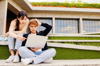 Üniversitedeki iki erkek ve kadın öğrenci, internetten öğrendiklerinin sınıftaki öğretmenlerin öğretileriyle uyuşmaması nedeniyle kafaları karışık ve şaşkın bir şekilde oturuyorlar: Eğitim kavramı.