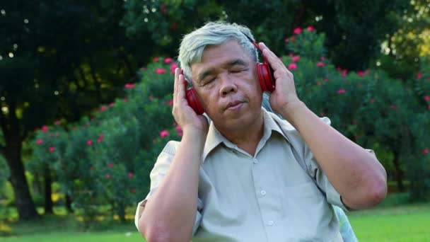 Aziatische Oudere Man Luisteren Naar Muziek Onderhoudend Met Oortjes Tuin — Stockvideo