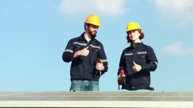 Erkek ve kadın elektrikçi mühendis bakım forkliftine biniyor. Güneş panelini teknisyen ekibi tarafından güvenlik için sıkılaştırılmış elektrikli matkap kullanılarak tamir ediliyor mu diye kontrol ediyor..