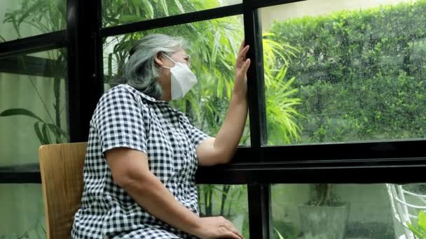 Azji Introwertyk Starsza Kobieta Masce Oglądanie Pory Deszczowej Przez Okno — Wideo stockowe