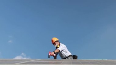 Güvenlik kaskı takan üst düzey erkek mühendis, çok yüksek yapılara güneş panelleri yerleştirmek için elektrikli matkap araçlarıyla modern güneş paneli sistemlerini denetleyen bir hava çalışma platformuna biniyor..