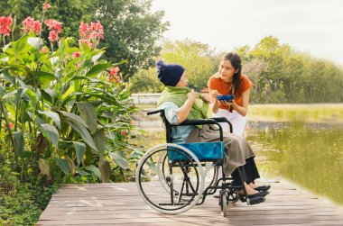 Asyalı bir aile, müteşekkir bir kız çocuğu hasta ve felçli bir anneye bakıyor, vücudunu iyileştirmek ve onu sağlıklı tutmak için yemeğini besliyor: