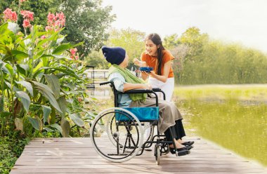 Asyalı bir aile, minnettar bir kız, hasta bir anneye bakıyor ve vücudunu iyileştirmek ve onu sağlıklı tutmak için yemeğini besliyor: