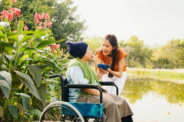 Asyalı bir aile, müteşekkir bir kız çocuğu hasta ve felçli bir anneye bakıyor, vücudunu iyileştirmek ve onu sağlıklı tutmak için yemeğini besliyor: