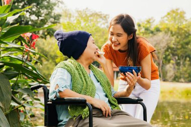 Asyalı bir aile, müteşekkir bir kız çocuğu hasta ve felçli bir anneye bakıyor, vücudunu iyileştirmek ve onu sağlıklı tutmak için yemeğini besliyor: