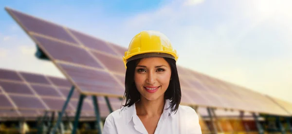 Beautiful cauasian female in yellow helmet working solar panel renewable energy clean energy green energy photovoltaic large scale solar panel power station provides supply power to urban industrial.