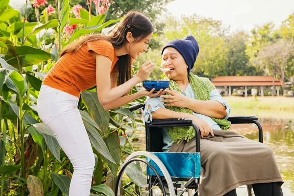 Asian family, grateful daughter takes care of mother who is sick and disabled with paralysis, feeds her food to restore her body and keep her healthy : Elderly insurance health care concept