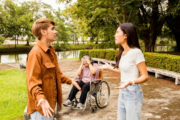 Son and daughter-in-law quarreling over parenting expenses disabled mother sick sitting in wheelchair debating loudly aggressively in front of mother causing stress depression negative problems family