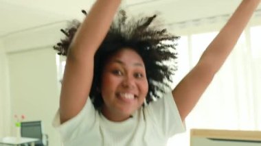 Portrait vibrant African American teenage girl dancing happily in her morning workout in her bedroom at home having fun after waking up early looking at camera and laughing.