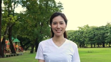 Portrait young asian woman walks gracefully in slow motion, smiles in a good mood and is in good health preparing for exercise in the garden in the morning.
