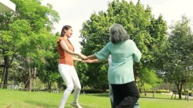 Moment cheerful asian family in the garden of three, elderly parents and daughter enjoy weekend in the park together holding hands, running around in circles, rejoicing, improving mental health.
