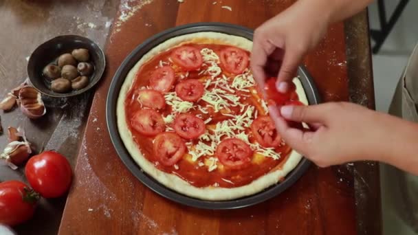 自家製のピザキッチンを作るキッチンの女性シェフは パルメザンチーズでマリネ生地の表面を飾るとオーブンのためのピザを準備おいしい細切り赤トマト — ストック動画