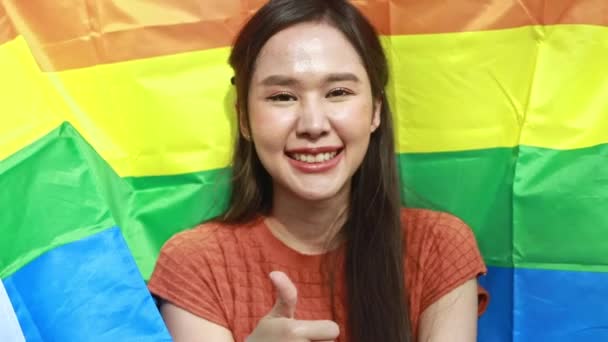 ポートレート若い美しいアジアの女性受け入れステータスLgbtqとともに笑顔の顔で良い気分で虹の旗と相まって 美しいLgbtqシンボルは カメラで最も幸せな見て — ストック動画