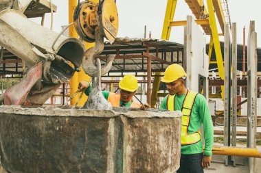 İki erkek işçi hazır beton kamyondan sıvı harç dökme işini incelemek için bir fabrikada önceden yapılmış duvar inşaatı için malzeme veya cep betonu araçları kullanıyor..