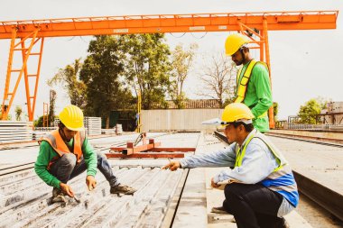 Group male workers preparing to cast materials working outdoors, construction yard casting precast concrete wall materials, planning to clean cast iron blocks, cement slab parts with brush. clipart