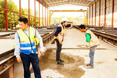 İş yerinde kask takmamak ve kazayı göze alarak onu uyardığı için güvenlik görevlisi erkek işçinin ihmalkârlığını azarlarken iş arkadaşları gergin duruyor..