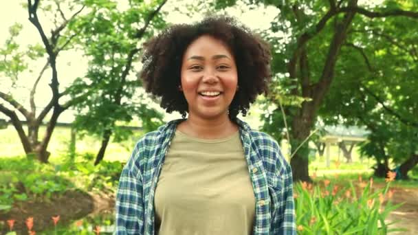 幸せな肖像画明るい顔と良い自然笑顔の若いアフリカ系アメリカ人女性が立っており 緑豊かな庭の環境を説明します 自分自身を楽しませ 良い精神にある — ストック動画