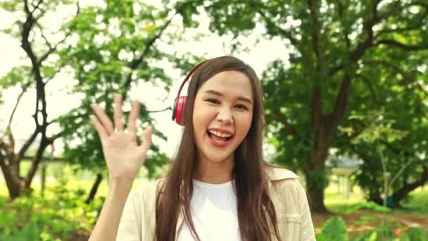 良い気分でヘッドフォンを持つアジアの女子大生は素晴らしい森林環境について説明しています — ストック動画