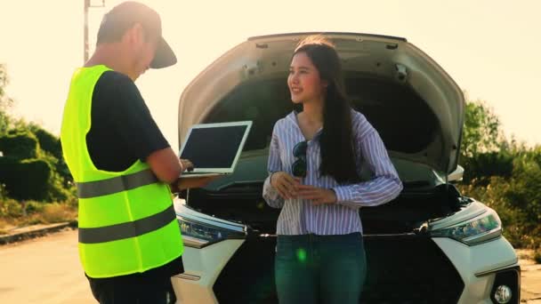 男性の整備士は 車が問題を解決するために道路で故障した若い女性によって記述された車の問題を記録します — ストック動画