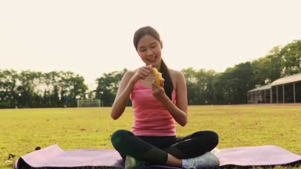 年轻的亚洲女人在运动前30分钟以良好的心情剥下香蕉 吃上30分钟 以帮助身体获得营养 准备运动所需的能量 不容易疲劳 — 图库视频影像