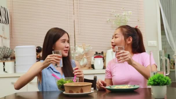 家の中で一緒に住んでいる2人の若いアジアの女性の日常生活 おいしいディナーは キッチンテーブルの上にサラダやスパゲティディナーに一緒に座って 親友の関係と世話をする — ストック動画