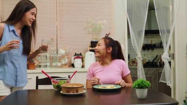 家の中で一緒に住んでいる2人の若いアジアの女性の日常生活 おいしいディナーは キッチンテーブルの上にサラダやスパゲティディナーに一緒に座って 親友の関係と世話をする — ストック動画