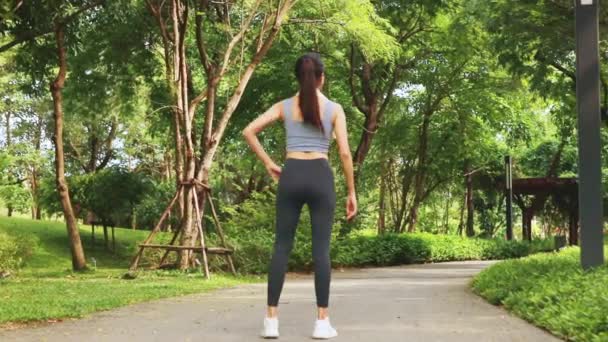 在阴凉的花园里锻炼的亚洲女人 回顾穿着性感运动服的年轻女人 抬起左腿和右腿防止受伤 运动保健和娱乐活动的概念 — 图库视频影像