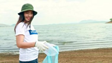 Portre gönüllüsü güzel Asyalı kadın gönüllüler plastik kutulardan çöp topluyor ve onları gönüllü ve gururla plastik torbalara koyup küresel ısınmayı azaltmak için geri dönüşüm toplumuna yardım ediyorlar..