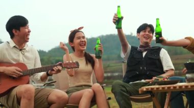 Mutlu günbatımları genç erkek ve kadınlardan oluşan Asyalı çeteler soğuk bira içerek bira şişeleriyle çatışıyor ve en iyi dostların arkadaşlığına katılarak gülüyorlar kamp partisi doğa aktiviteleri sırasında..