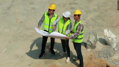 Üst düzey kadın mimar, iskelenin yanında duran ve binanın düzeltilmiş noktalarını gösteren iki erkek işçiye danıştı ve yukarıdaki ekibe aynı yolu takip etmelerini söyledi.