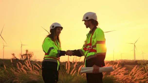 在农场风力涡轮机维修工作于日落时分成功地完成后 男女工程师握手祝贺 — 图库视频影像