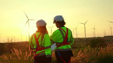 İki elektrik mühendisi, erkek ve kadın enerji üzerinde çalışıyor. Temiz ve çevre dostu elektrik üretmek için rüzgar türbinleri kullanıyorlar. Bakım kontrolleri için çevre dostu planlar..