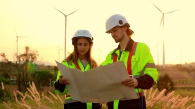 İki elektrik mühendisi, erkek ve kadın enerji üzerinde çalışıyor. Temiz ve çevre dostu elektrik üretmek için rüzgar türbinleri kullanıyorlar. Bakım kontrolleri için çevre dostu planlar..