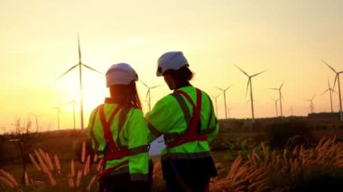 İki elektrik mühendisi, erkek ve kadın enerji üzerinde çalışıyor. Temiz ve çevre dostu elektrik üretmek için rüzgar türbinleri kullanıyorlar. Bakım kontrolleri için çevre dostu planlar..