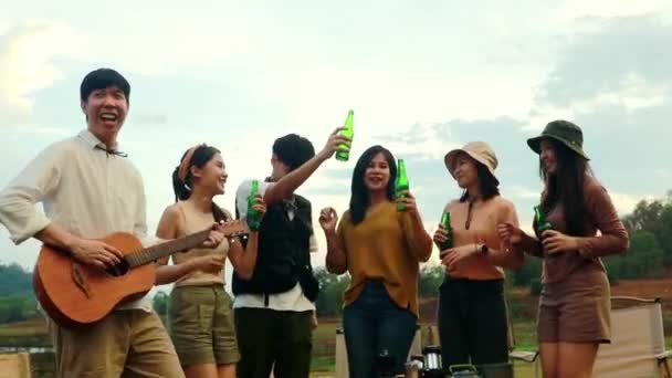 アジアのギャングの男の子と女の子は ビール瓶を粉砕し 喜んで笑う冷たいビールの上にギターを歌うトーストを演奏し イベントキャンプパーティー中に親しい友人の友情の親善に参加します — ストック動画