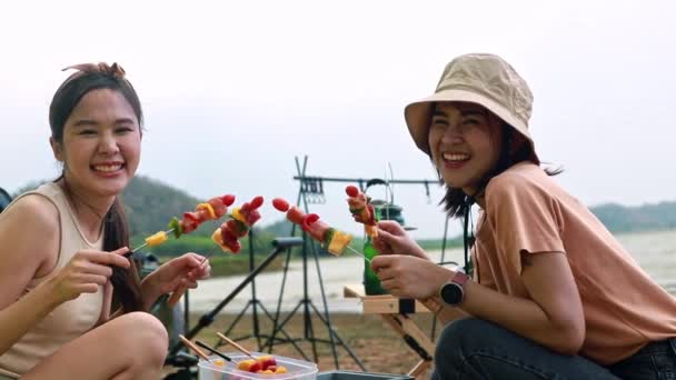 ホリデーキャンプ活動 バーベキュースパイスを嗅ぐ2人の幸せで興奮したアジアの若い女性は 一晩テントで寝ている間に美味しいバーベキュー食品を準備します — ストック動画