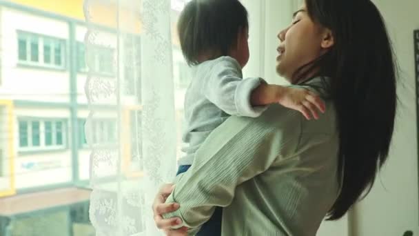 窓から寝室に立っているかわいい娘を抱えている肖像画の母 — ストック動画
