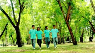 Mutlu Asyalı genç erkekler ve kadınlar çevreyi korumak için gönüllü ağaç dikiyorlar bahçede birlikte yürüyüp, birbirlerine sarılıyorlar ve ağaç dikiyorlar..