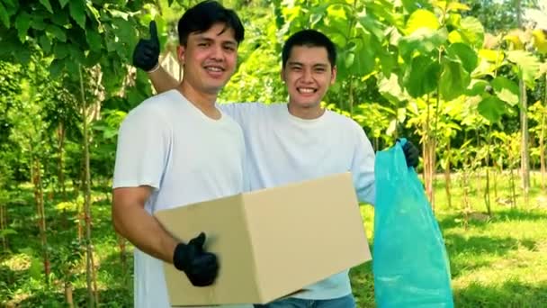 Praca Dobrowolna Dwóch Przystojnych Ochotników Azjatyckich Uśmiechniętych Szczęśliwie Trzymać Pudełka — Wideo stockowe