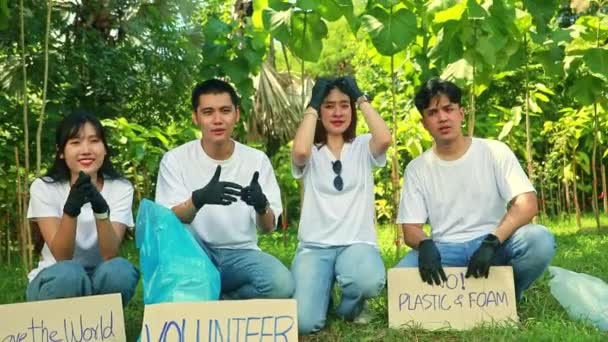 グループ アジアの男性と女性のボランティアは一緒に黒い手袋を着用し 汚れから細菌がゴミを拾うのを防ぎ 環境を節約するペーパー サインを準備します — ストック動画