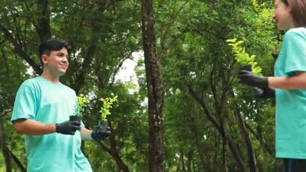 一对年轻的亚洲男女志愿者带着树苗散步 植树以保护环境 增加绿化 让我们一起在花园里成长 骄傲地微笑着 — 图库视频影像
