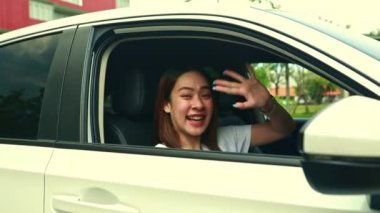 Mutluluk genç kız öğrenci araba sürerken olumlu hisler ifade eder, pencerenin kenarında rahatça güler, üniversitede okuduktan sonra ayrılmaya hazır, güvenle araba sürer.