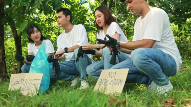 亚洲男性和女性志愿者坐在一起 戴着黑色手套 一起清洁污垢 准备捡垃圾 准备宣传环保的纸牌 — 图库视频影像