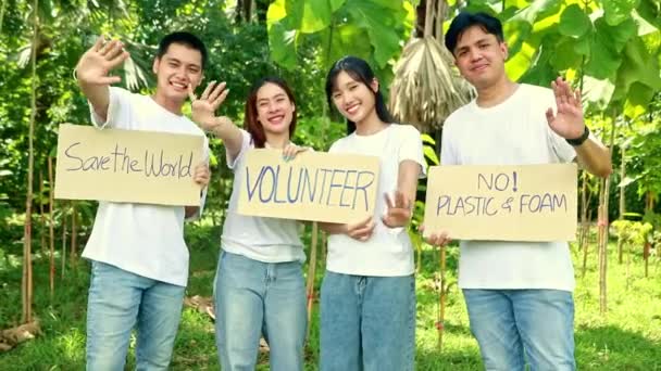 グループアジアの男性と女性ボランティアは 紙バナーキャンペーン環境保護を廃棄し 森林植林活動における汚染を引き起こすプラスチックや泡の使用を控えています — ストック動画