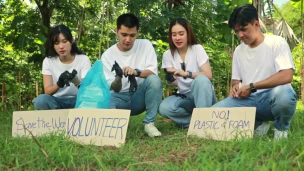 亚洲男性和女性志愿者坐在一起 戴着黑色手套 一起清洁污垢 准备捡垃圾 准备宣传环保的纸牌 — 图库视频影像