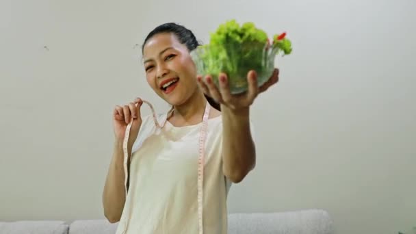 陽気で幸せなアジアの女性ライフスタイル トマトのボウルを保持するサラダを食べる ベルペッパー 新鮮な野菜や測定テープ 体重を減らしたいです スリムで健康的な滞在 — ストック動画