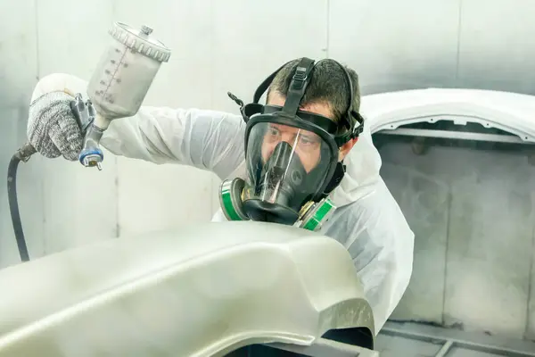 Automotive paint services : Male painters who are skilled in using automotive paint sprayers wearing masks to prevent spray paint dispersion work in a closed spray booth for health and quality work.